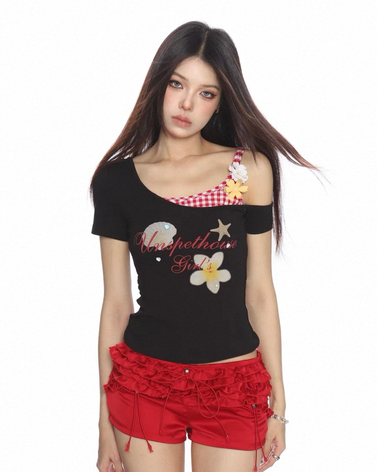 Woman wearing a black top with floral designs and red shorts on a white background