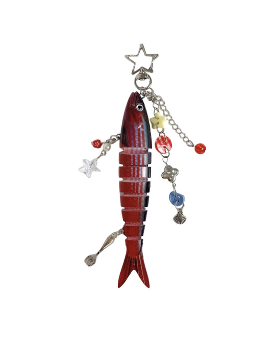 Decorative fish-shaped ornament with charms on a white background