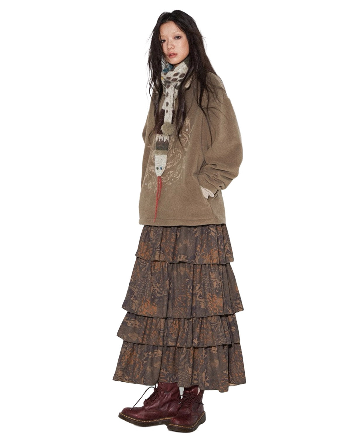 Person wearing a layered outfit with a jacket and skirt on a white background