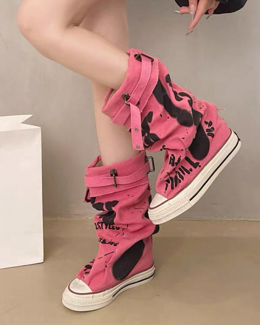 Pink high-top sneakers with black designs worn by a person on a neutral background