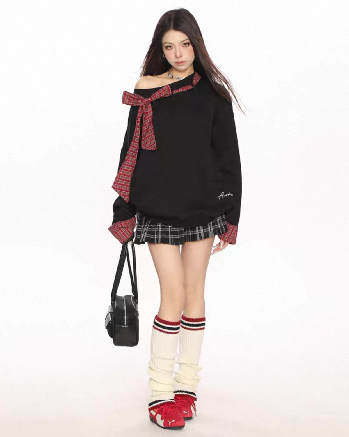 Person wearing a black off-shoulder top with red plaid accents, a plaid skirt, and knee-high socks with a white background.