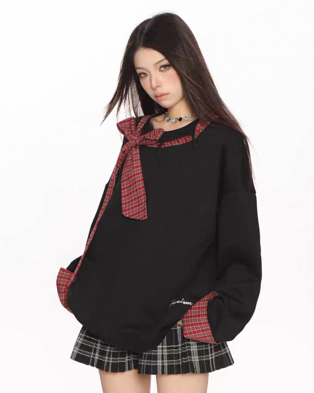 Black sweater with plaid accents and a skirt on a white background
