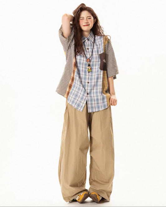 Person wearing a plaid shirt, vest, and beige pants on a white background
