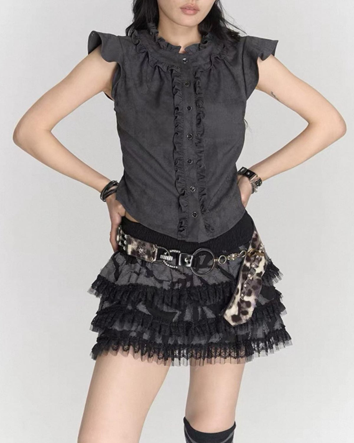 Person wearing a black ruffled top and skirt with leopard print accents on a white background