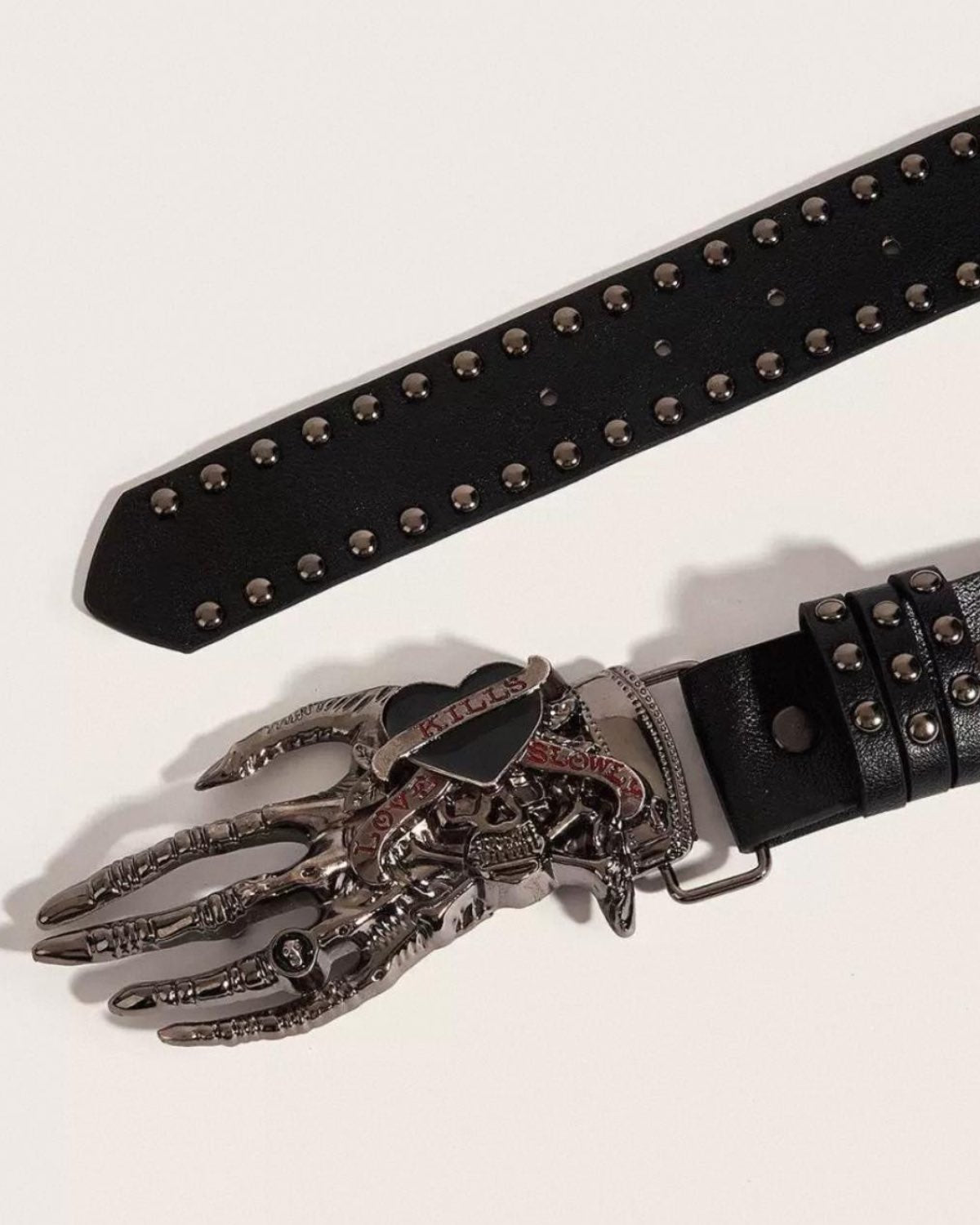 Black belt with silver studs and a decorative metal buckle on a light gray background