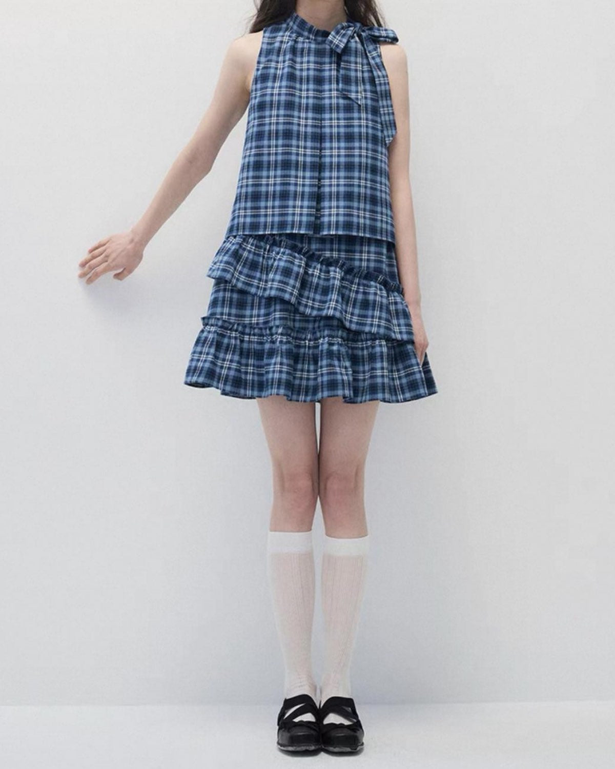 Person wearing a blue plaid dress with a white background, headless shot