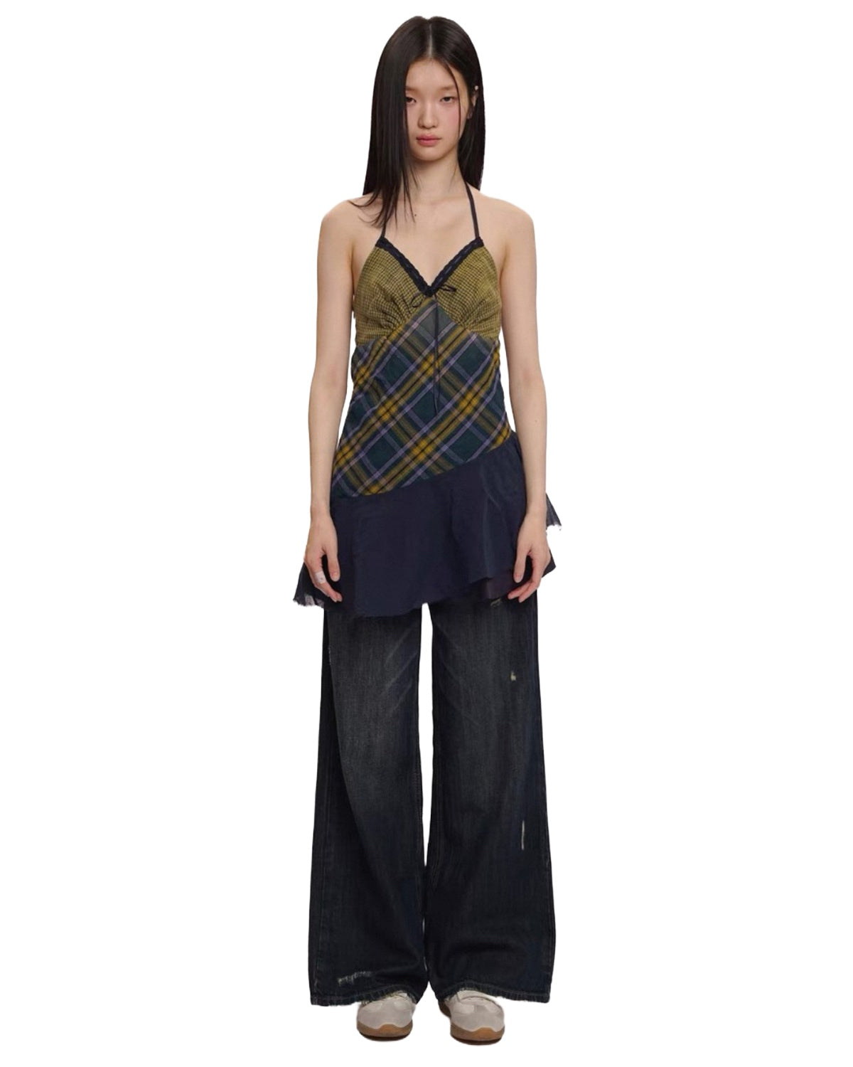 Woman wearing a plaid top and black pants on a white background