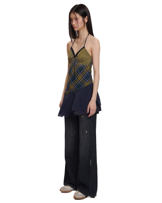 Woman wearing a plaid top and dark pants on a white background