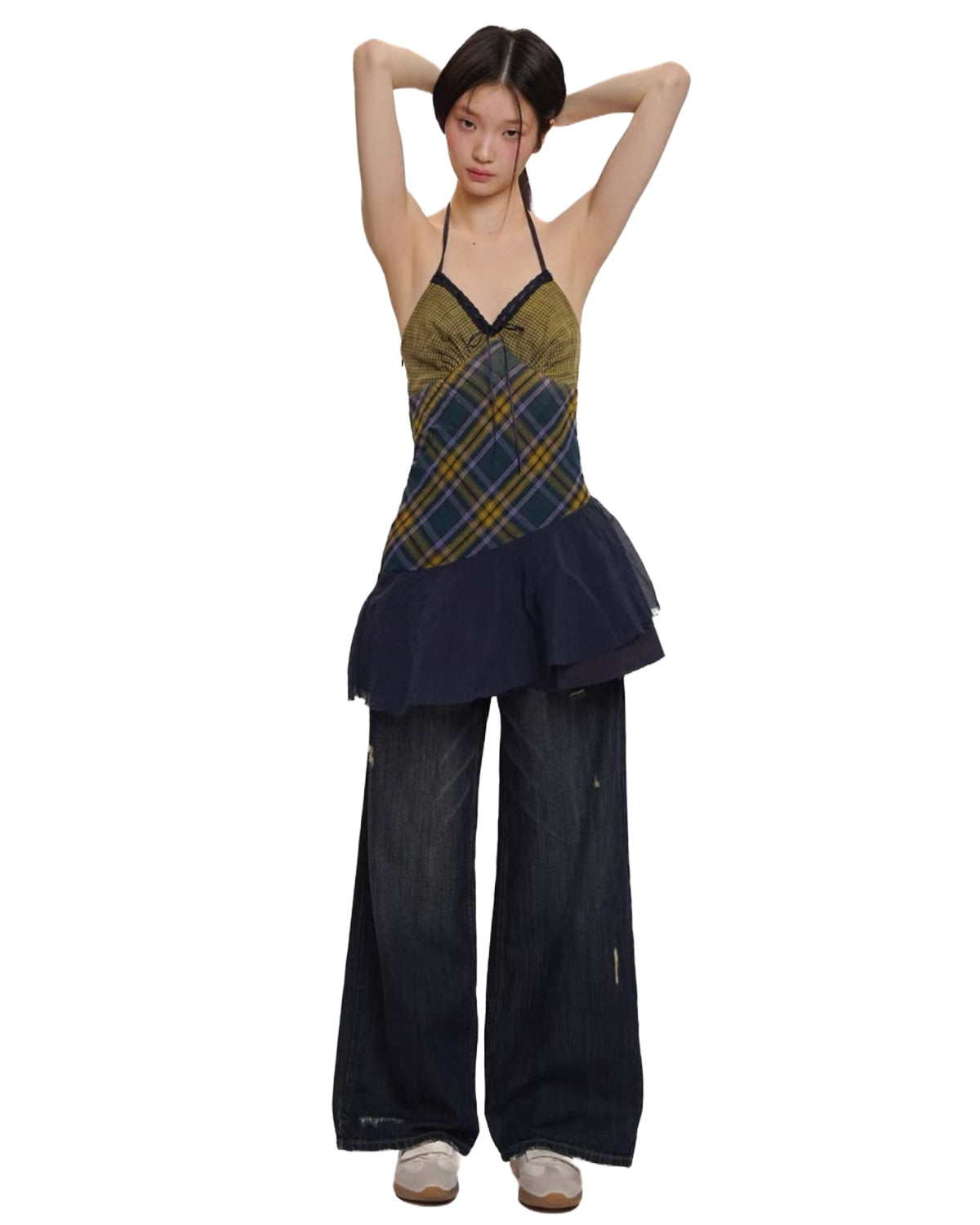 Woman wearing a plaid top and dark pants on a white background