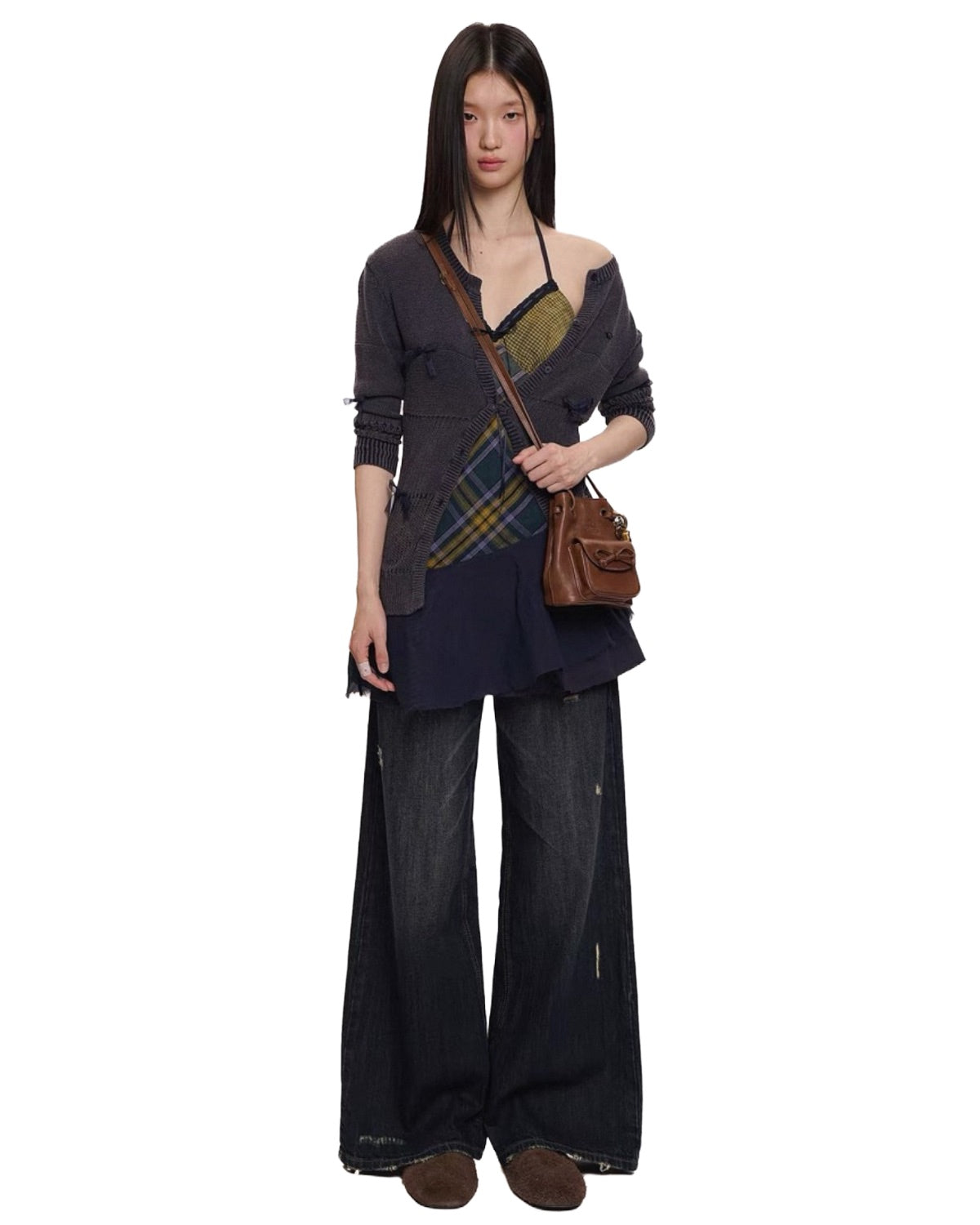 Woman wearing a layered outfit with a plaid bag on a white background