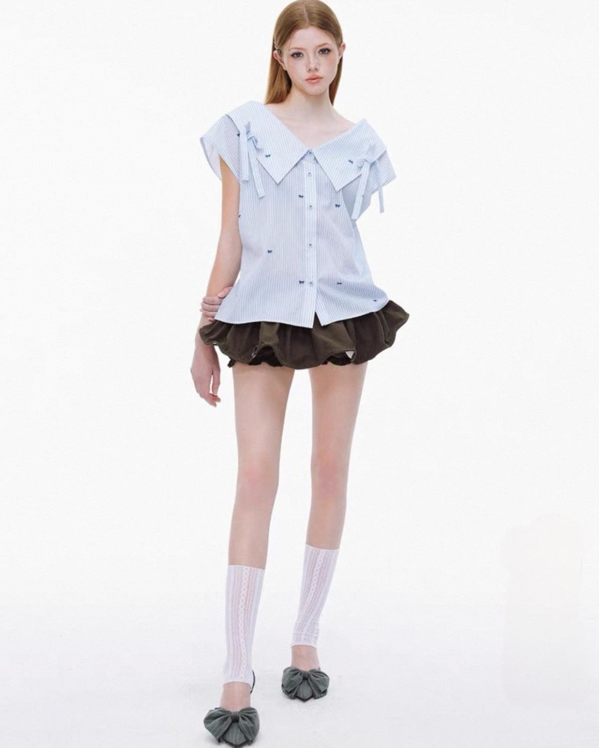 Model wearing a white blouse with ruffled details and a black skirt on a white background