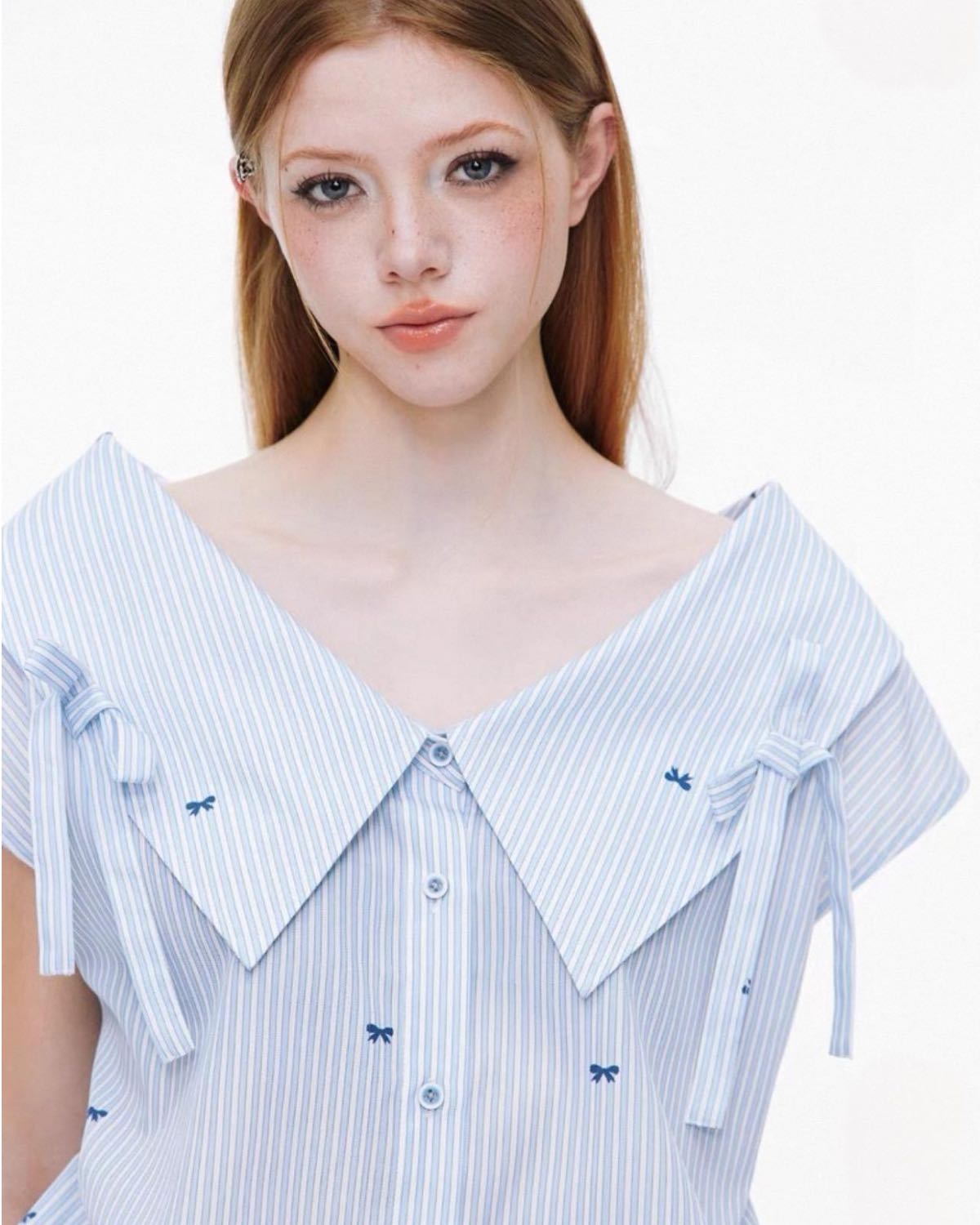 Woman wearing a blue and white striped dress with bow details on a white background