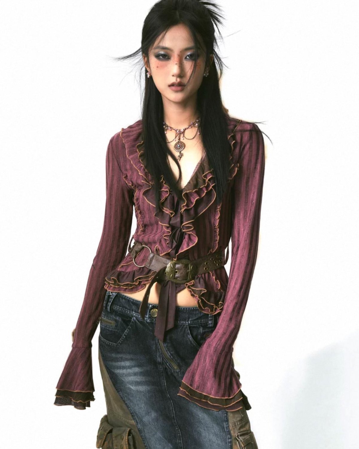 Person wearing a purple ruffled blouse and blue jeans on a white background