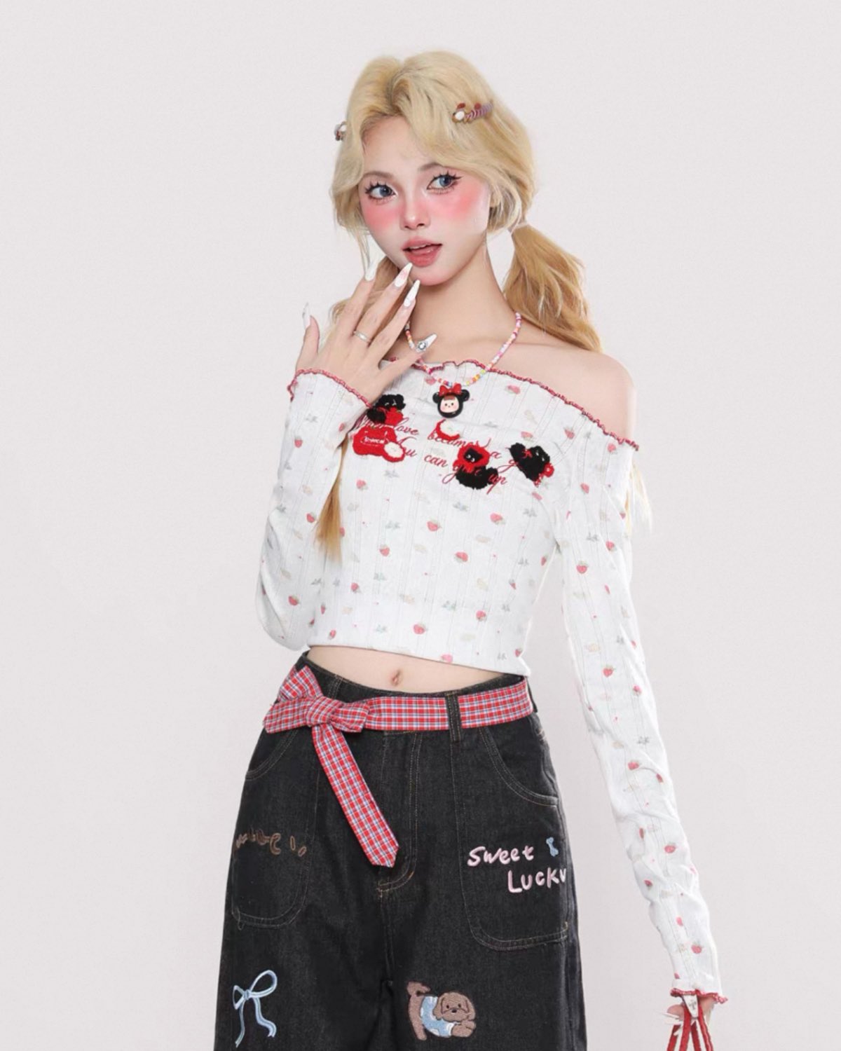Person wearing a white long-sleeve top with red and black designs and black pants with text and graphics.