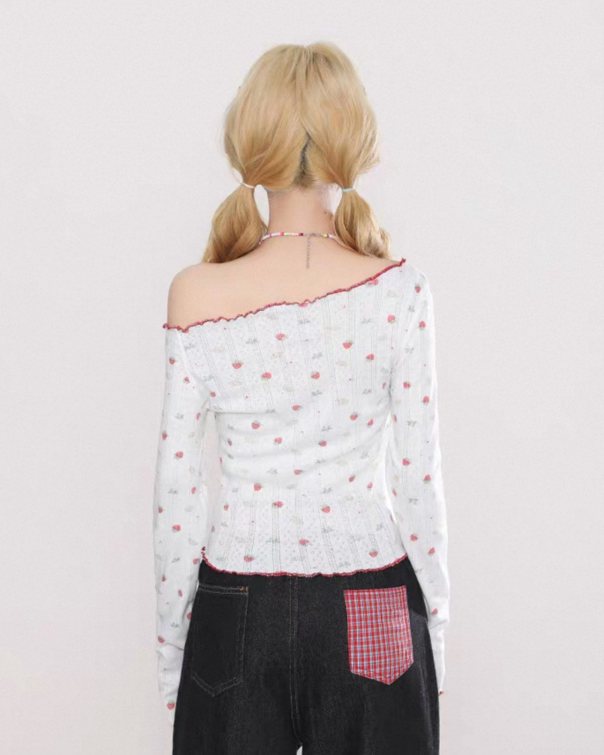 Person wearing a white blouse with red accents and black pants on a light gray background