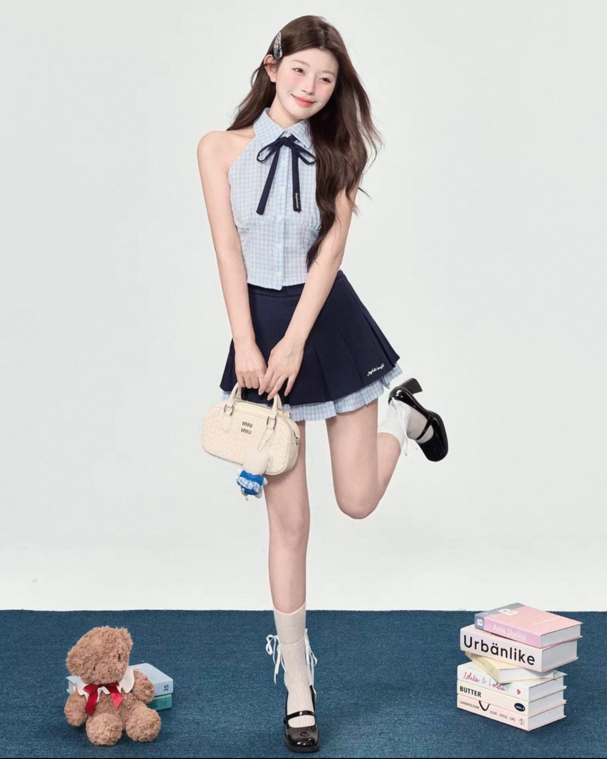 Woman in a school uniform with a teddy bear and books on a blue floor.
