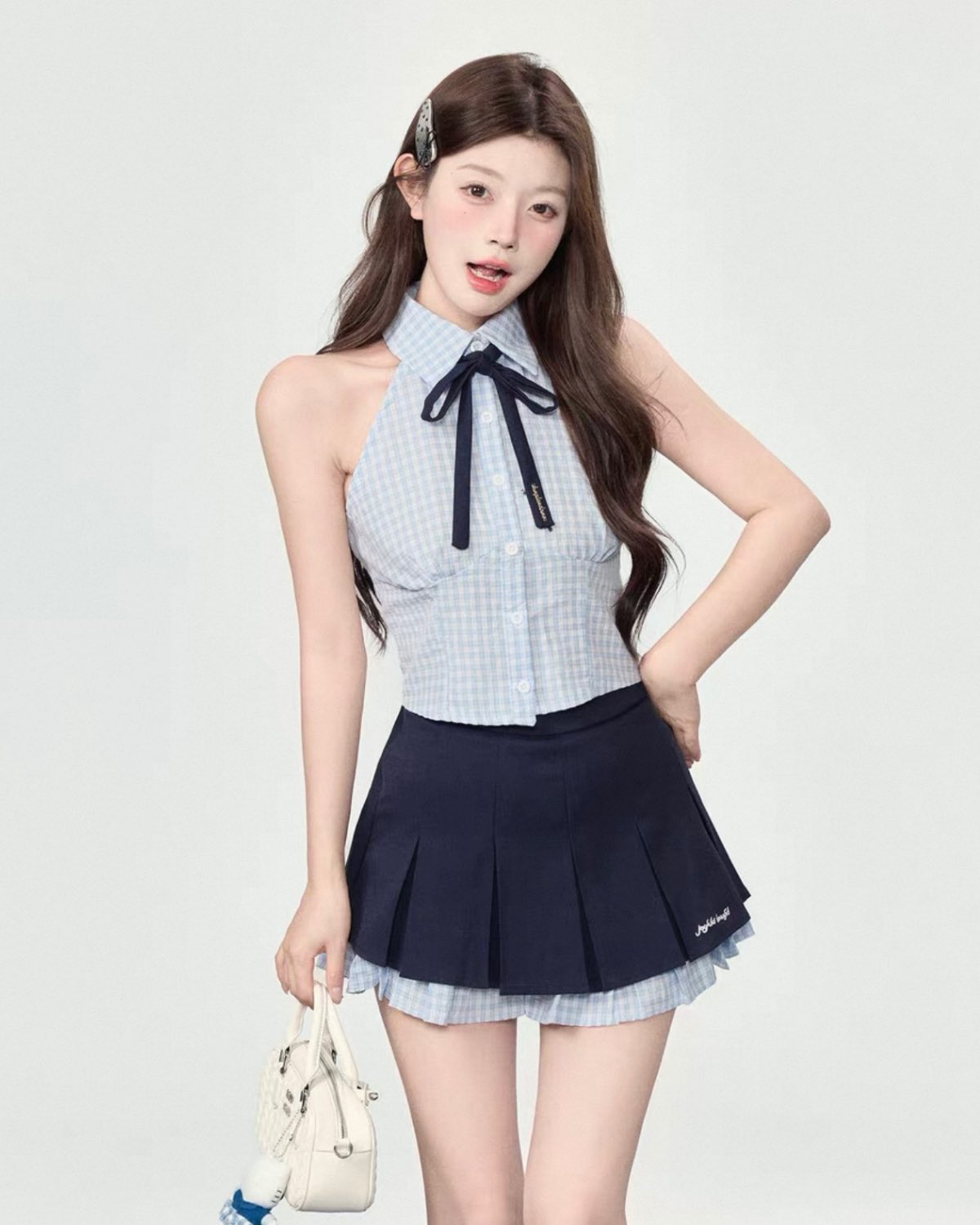 Woman wearing a checkered top with a bow and pleated skirt on a white background