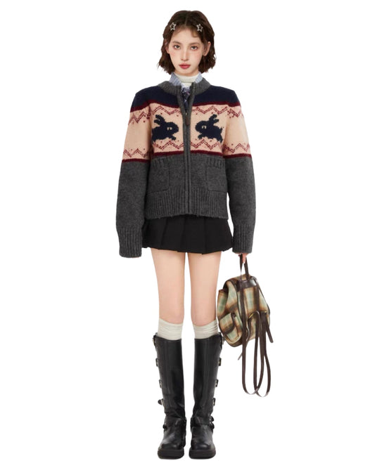 Person wearing a patterned sweater with rabbit designs, black skirt, and black boots on a white background.