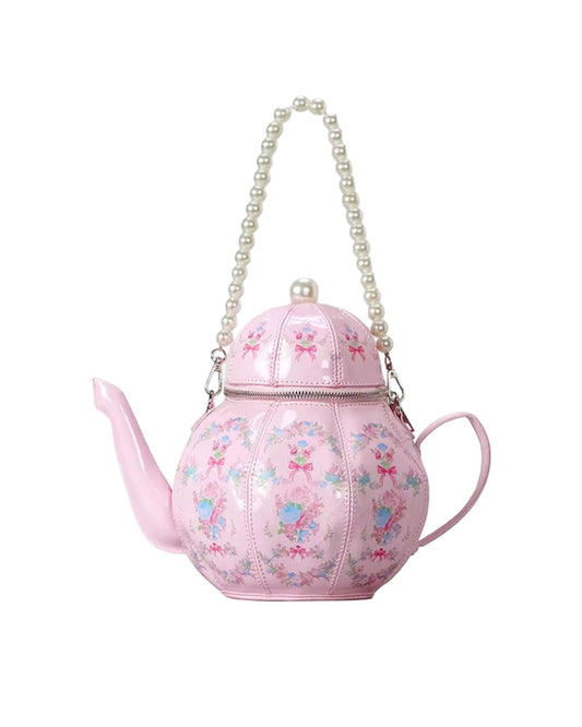 Pink teapot-shaped handbag with floral design and pearl handle on a white background