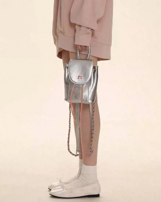 Person wearing a silver backpack with a beige background