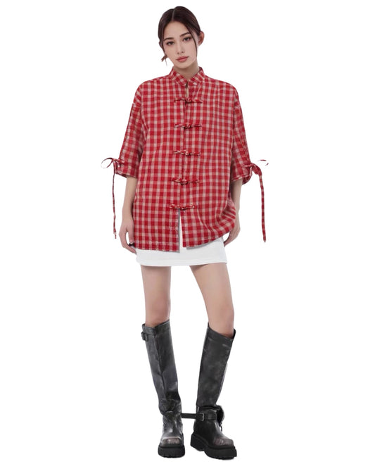 Person wearing a red checkered shirt with tied sleeves and black boots on a white background