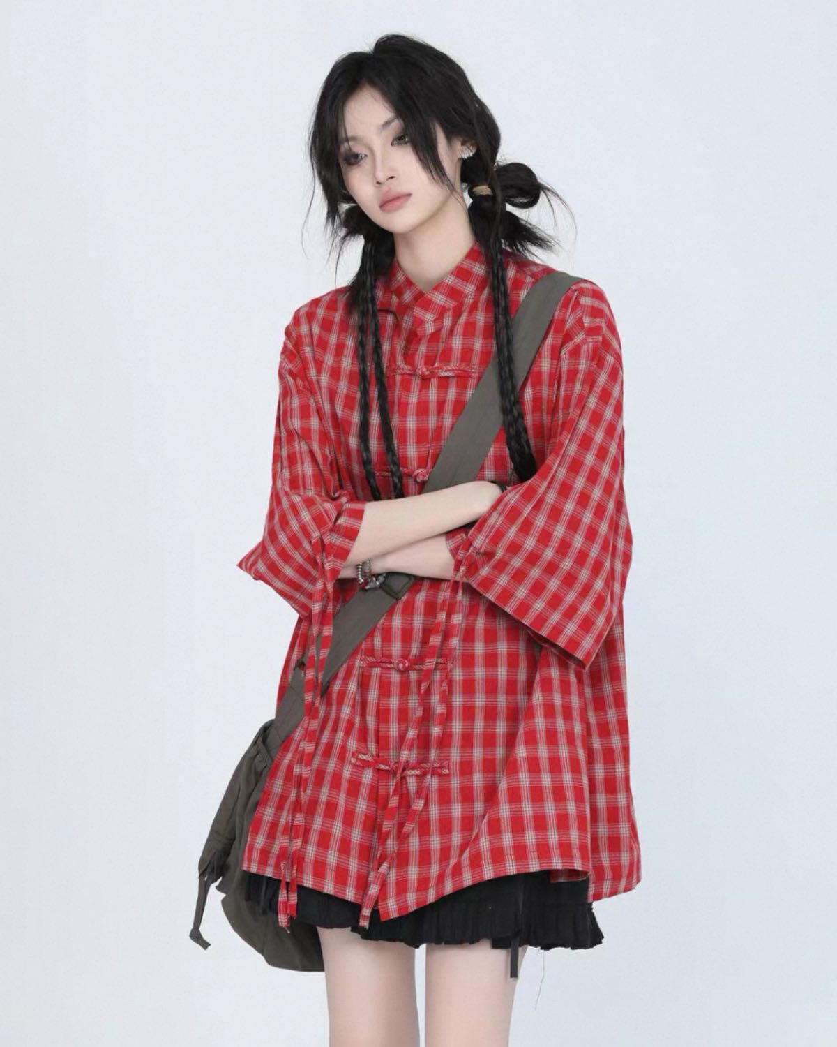 Person wearing a red and white checkered shirt with a black skirt on a white background