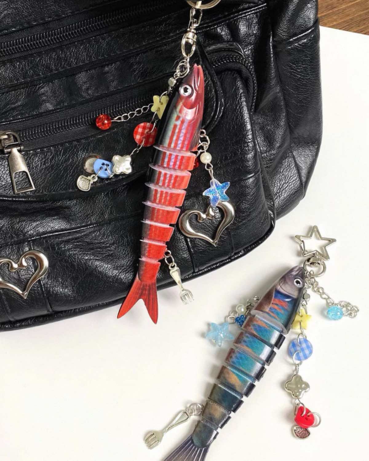 Fishing lure keychain with charms attached to a black leather bag.