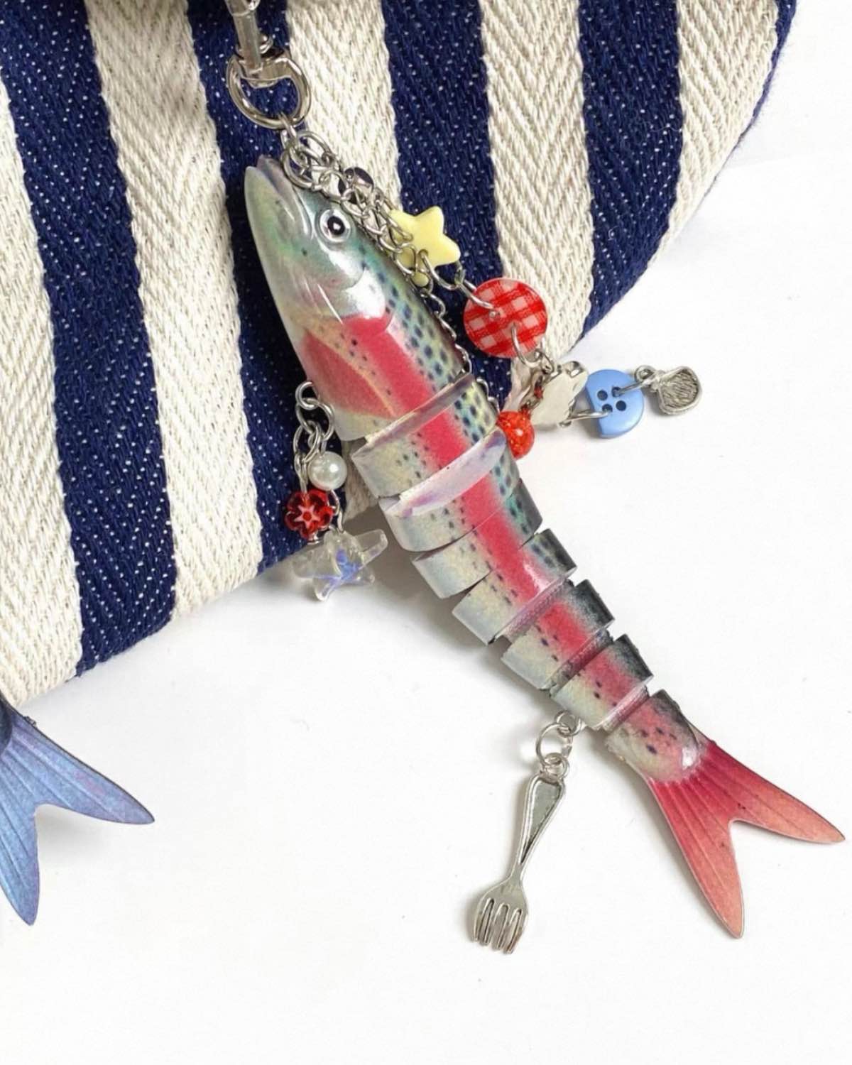 Colorful fishing lure with charms on a striped fabric background