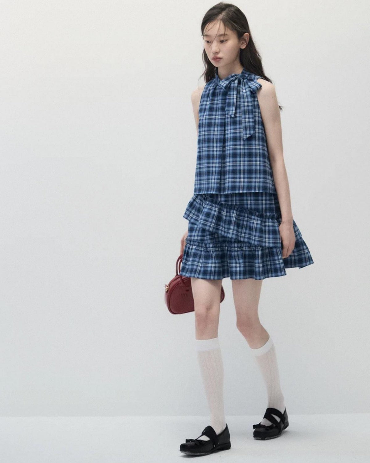Woman wearing a blue plaid dress and walking with a white background