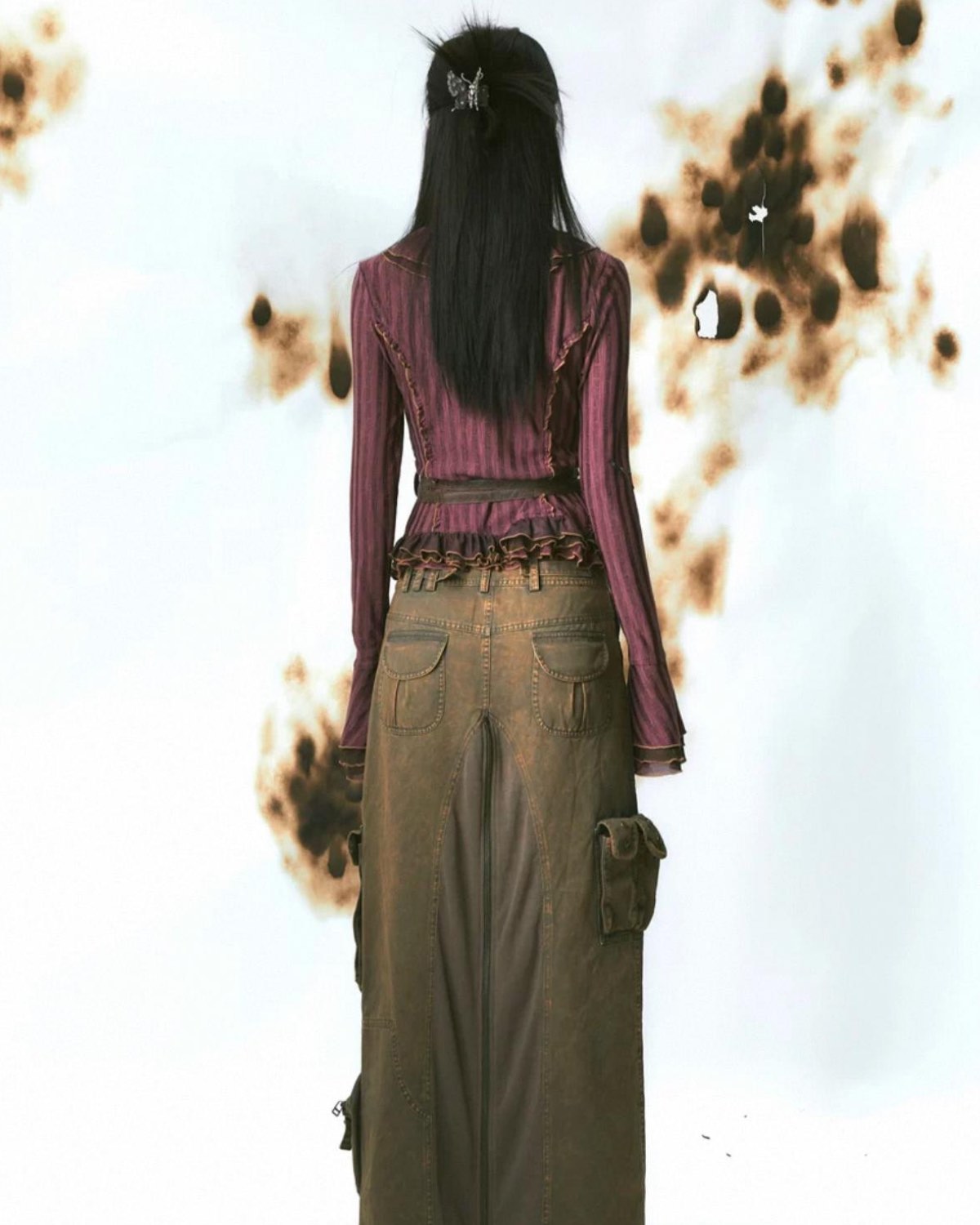 Person wearing a purple top and brown pants with a white background