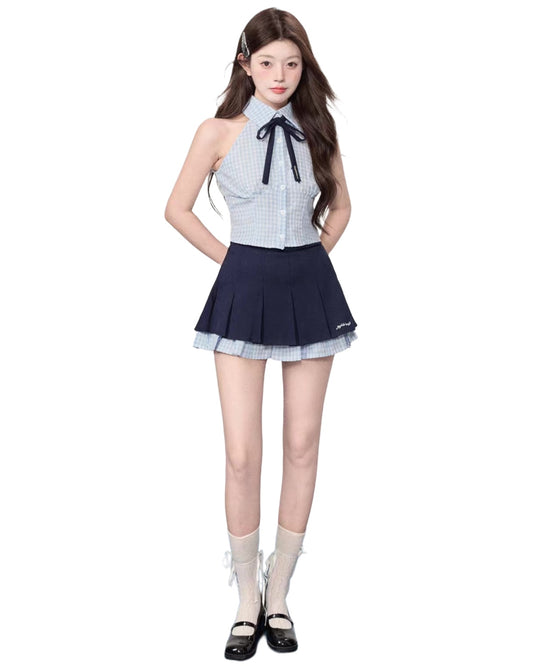 Woman wearing a checkered top and navy pleated skirt on a white background